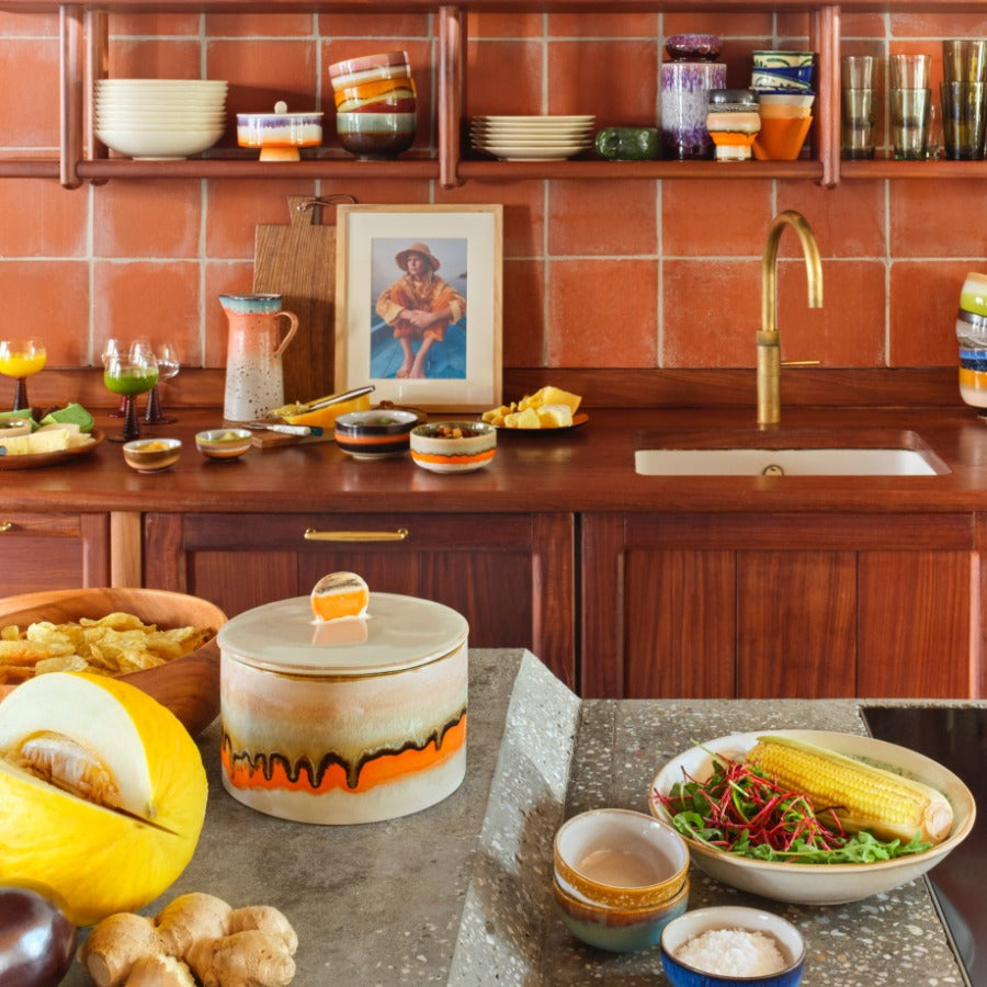 birght and colourful kitchen scene with deep red wood cupboards further lifted in mood by a number of pieces from the HKliving 70s collection just sparking joy at every viewpoint