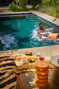 Terra stoneware side table by HKLIVING used as a poolside accent table with a wine glass