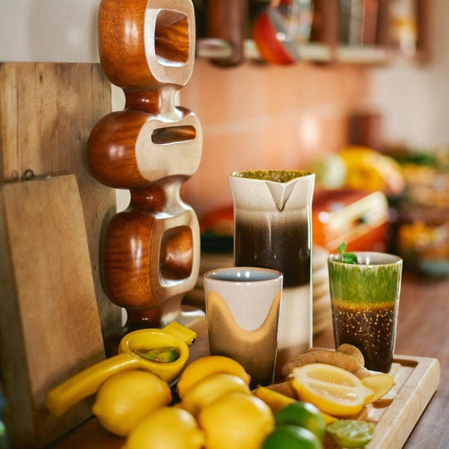 kistchen worktop with a large wooden piece of artwork from hkliving and tea mugs and coffee jug surrounded by lemons and limes in a very nordic or danish style