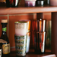 stacks of tall mugs on a shelf in colourful 70s colours with pinks brownsa and orange