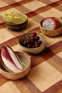 Four HKLIVING Drift tapas bowls filled with Chinese cabbage, dragon fruit, red grapes and radicchio, arranged on an orange checked tablecloth
