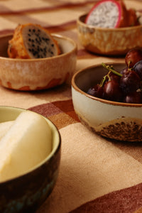 A close-up view of the HKLIVING Drift tapas bowls filled with dragon fruit, red grapes and sliced pear, styled on an orange checked tablecloth