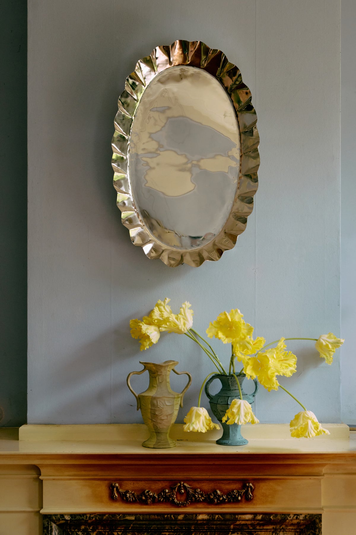 Large HKLIVING New Classics chrome tray hung on a pale blue wall above a fireplace, with yellow daffodils in a vase below