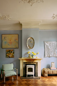 Living room with the Large HKLIVING chrome tray hung on a pale blue wall beside an open fireplace and armchair