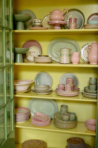 70s Ceramics teapot in Slush displayed on a glass shelving unit alongside plates, bowls, cups and other pieces from HKLIVING's collection