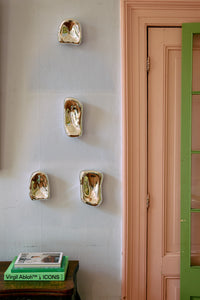 Four HKLIVING chrome glass wall sculptures mounted in a vertical cluster beside a pink and green painted door frame