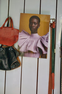 Reverie plexi portrait by HKLIVING propped against a wall beside vintage bags and belts