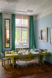 Offset framed artwork by HKLIVING hung on a blue wall above a dining table with green curtains