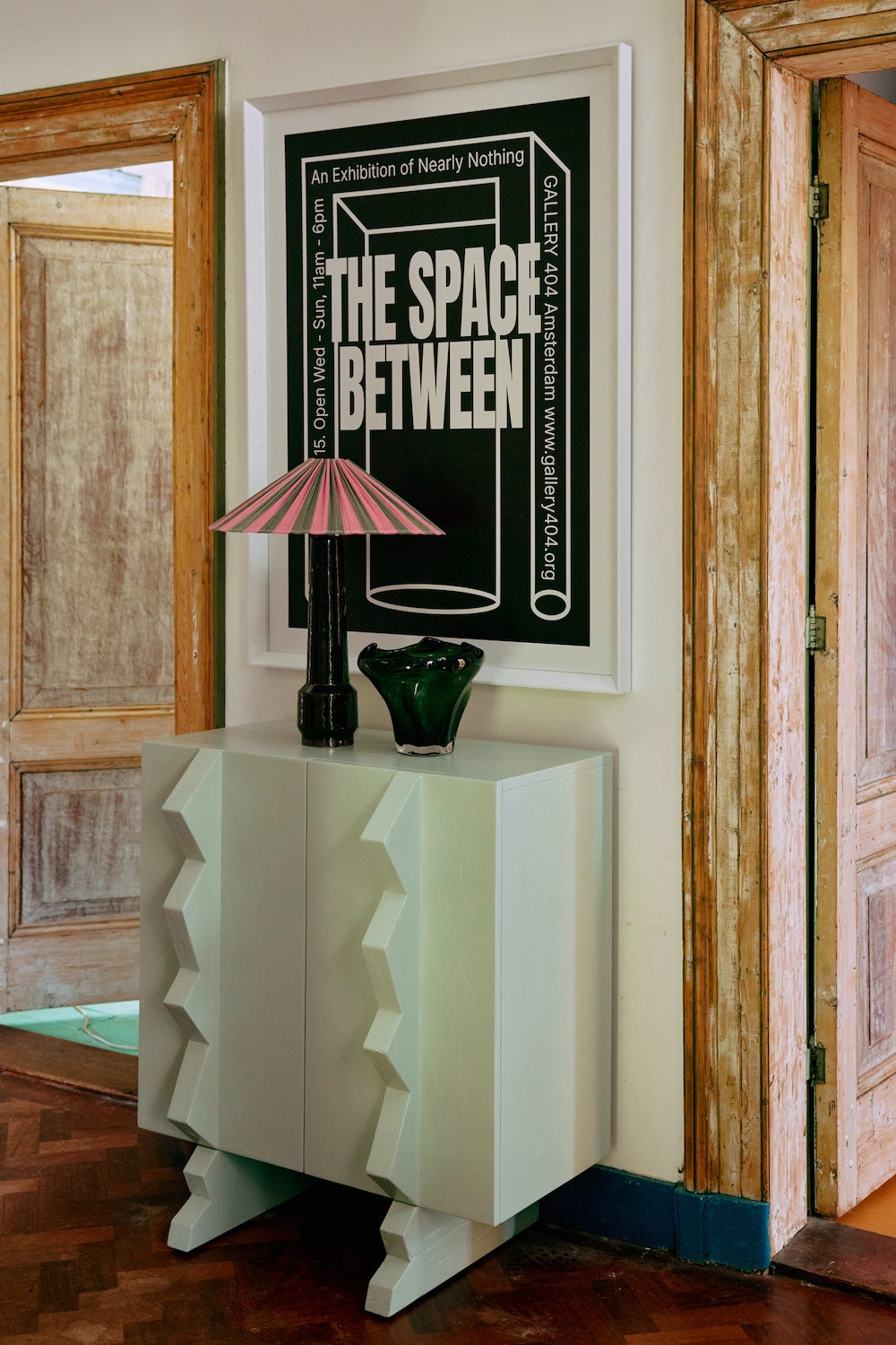 Between Space framed poster by HKLIVING hung above a mint console cabinet with a table lamp