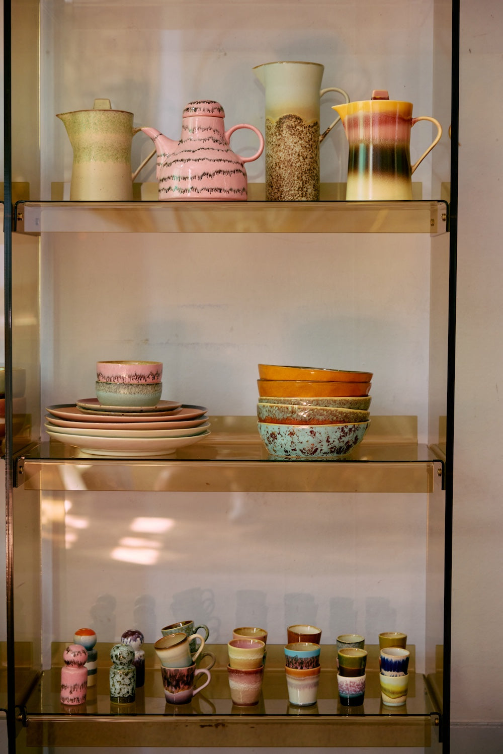 70s Ceramics pasta bowls in Patina displayed on a glass shelving unit alongside jugs, plates and cups from HKLIVING's collection