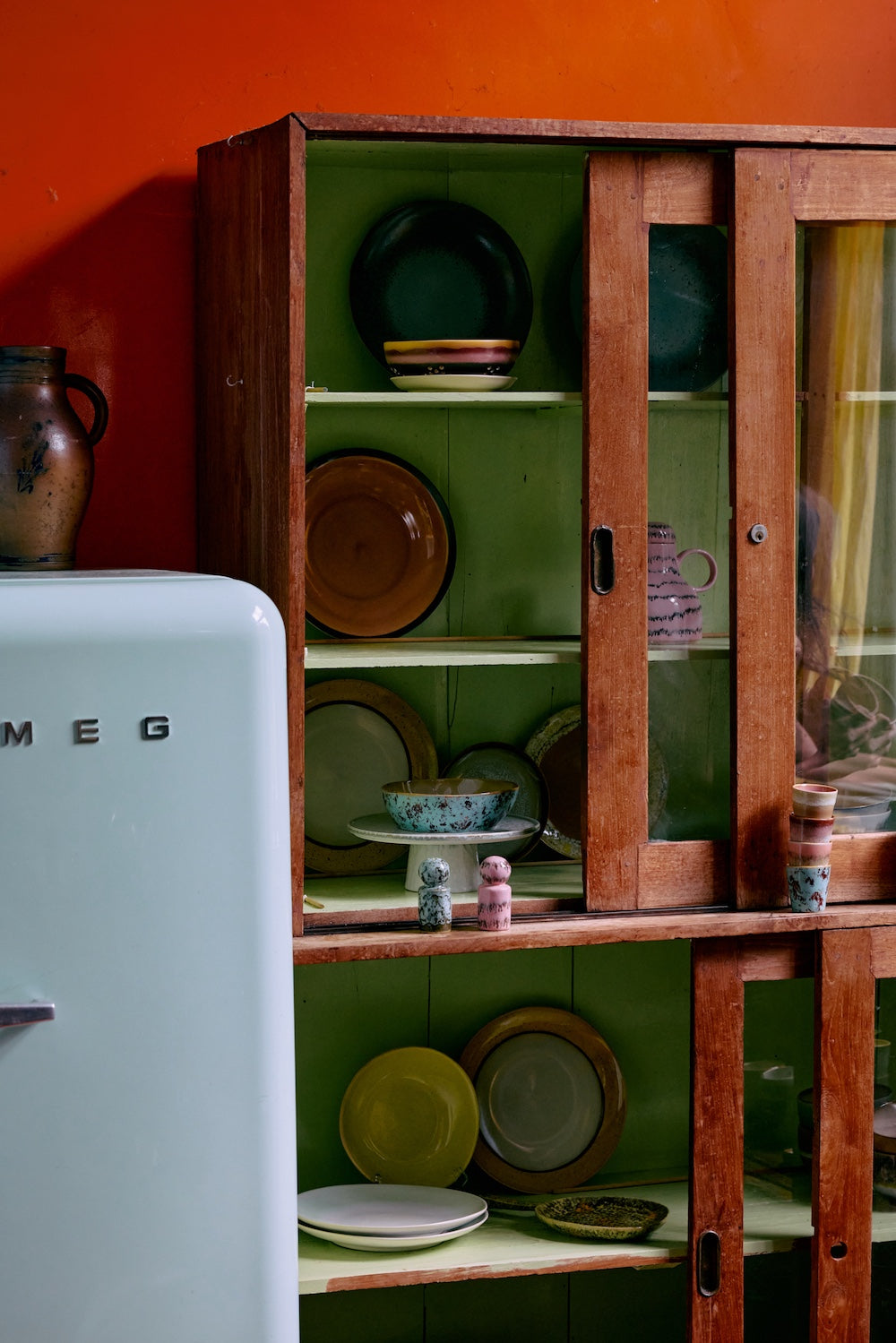 70s Ceramics pasta bowls in Patina displayed in a wooden cabinet alongside plates and mugs from HKLIVING's collection, beside a pale green fridge