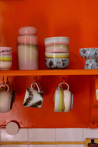 Pink, sage green and cream ombre 70s Ceramics storage jar by HKLIVING with a domed lid, displayed on an open kitchen shelf with mugs and bowls from the same collection