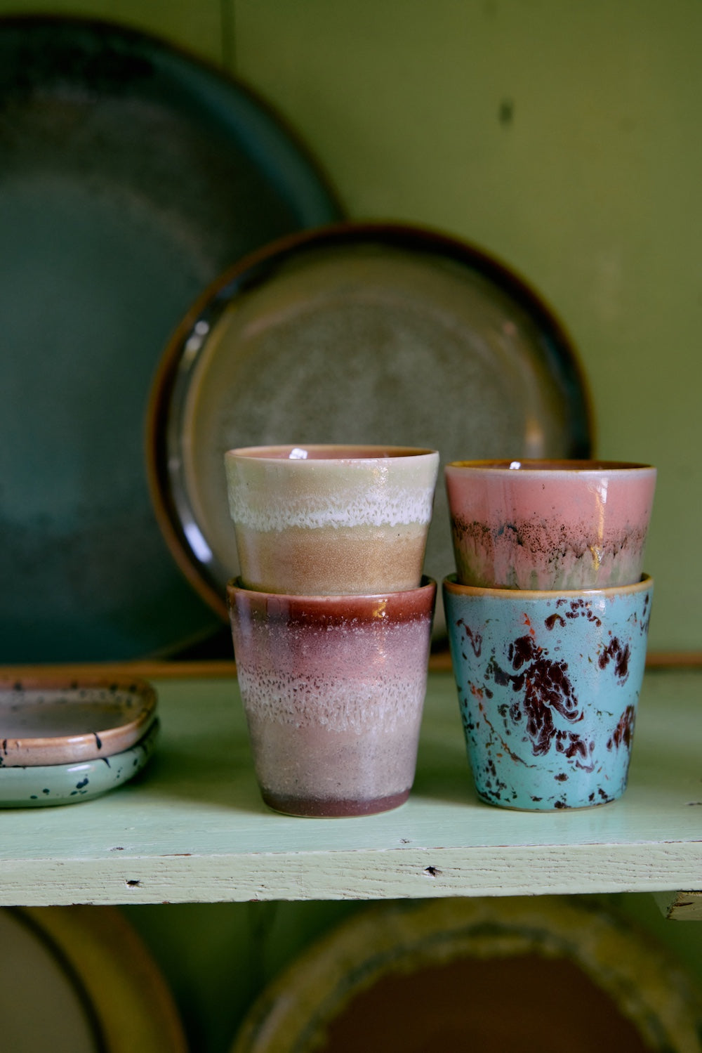 The HKLIVING Futurism ristretto mugs displayed on the bottom shelf of a tall glass and brass unit, alongside jugs, bowls and plates from the 70s ceramics collection