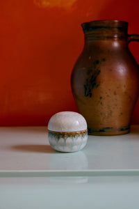 Small round 70s Ceramics sugar pot in Petal by HKLIVING, with a pale sage green and cream glaze, styled beside a rustic stoneware pitcher against an orange wall