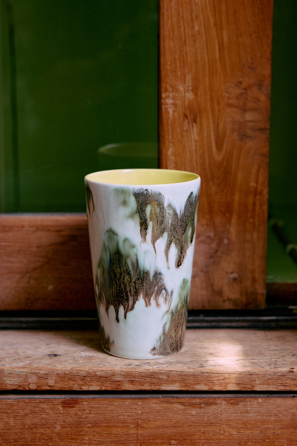 The HKLIVING Tide tea mug stood on a wooden windowsill against a green painted door