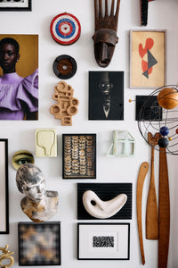 The HKLIVING brutalist wall sculpture as part of a curated gallery wall, surrounded by framed artwork, a carved wooden mask, a target sculpture and other found objects