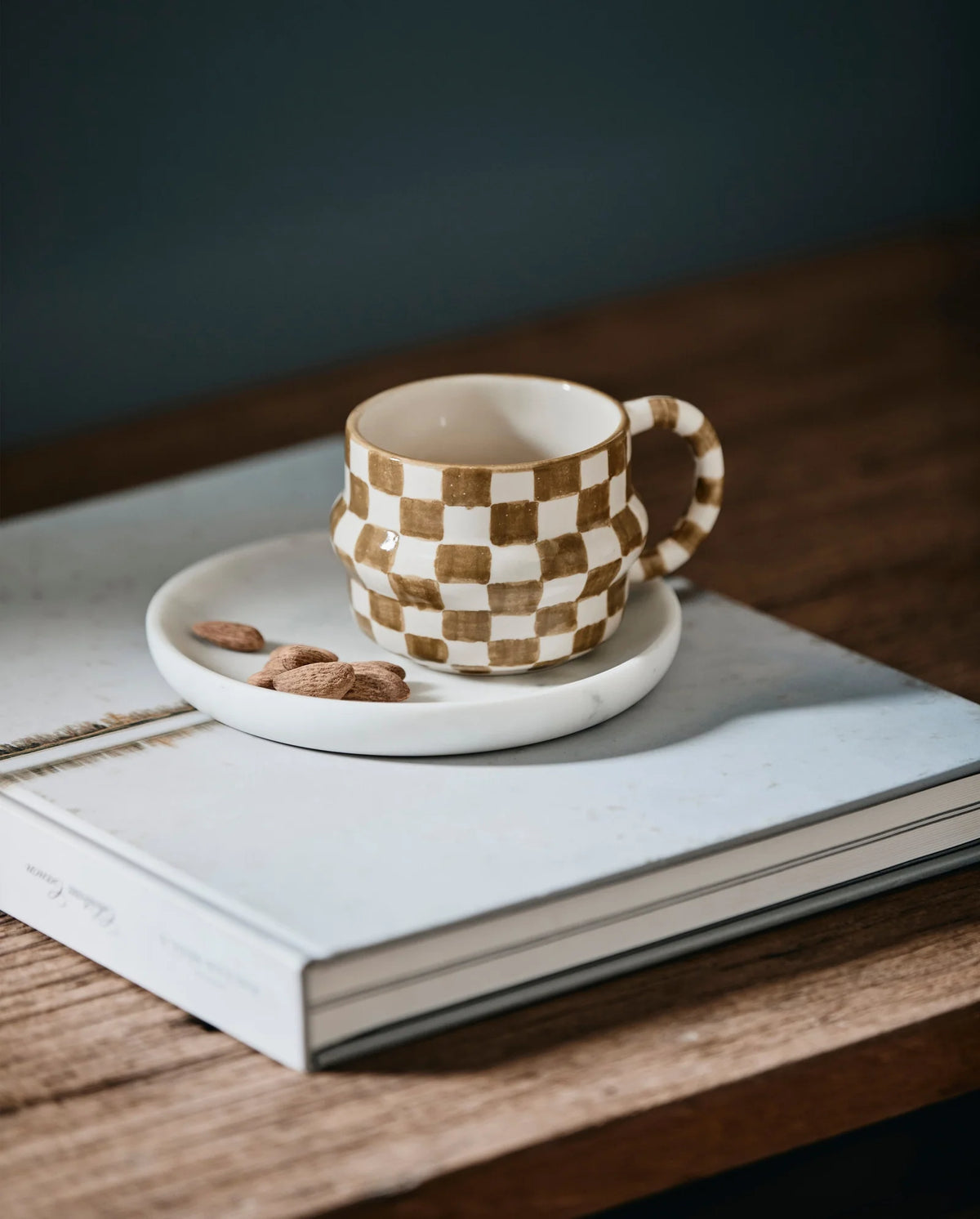 White marble dish by Nordal styled with a checkered mug and almonds on a book