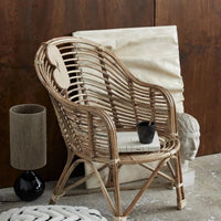 the bhsiny black lamp base and jute lamp shade are set up behind a cane chair: not sure why it's sat on the floor but it looks pretty in an odd way