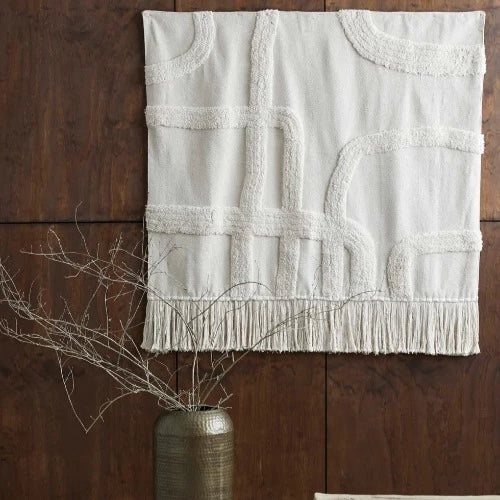 fabric cotton wall rug with a large metal vase with decorative twigs infront of it