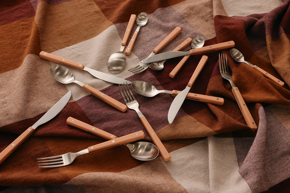 HKLIVING 70s Cutlery with peach handles scattered across a rust and brown linen cloth
