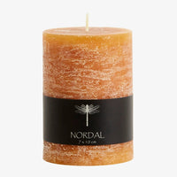 amber yellow orange pillar candle with a black nordal label wrapped around it