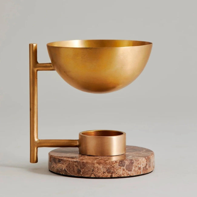 brass bowl held above a brass votive candle holder on a disc of pink brown marble from nordal to frangrance a room