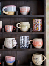 Collection of ceramic mugs on a dark wooden shelf