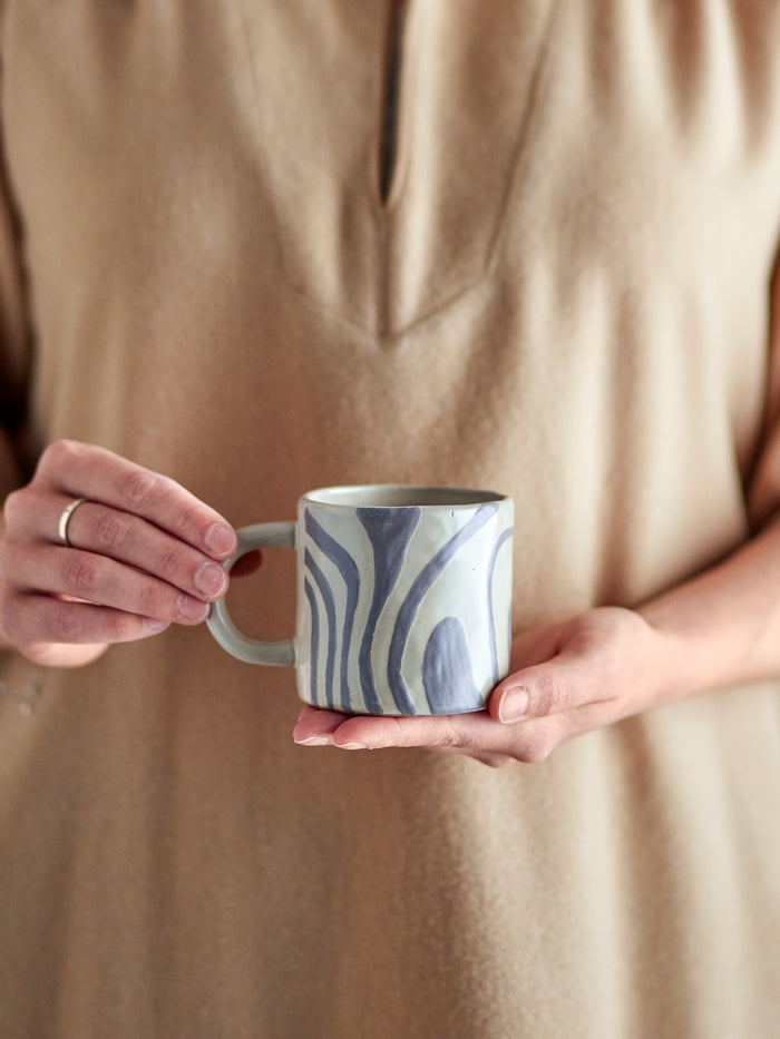 person holding grey ninka mug showing hand-decorated glaze