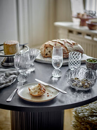 Taurin glasses on a round dark table with sourdough bread, a plate and a glass bowl