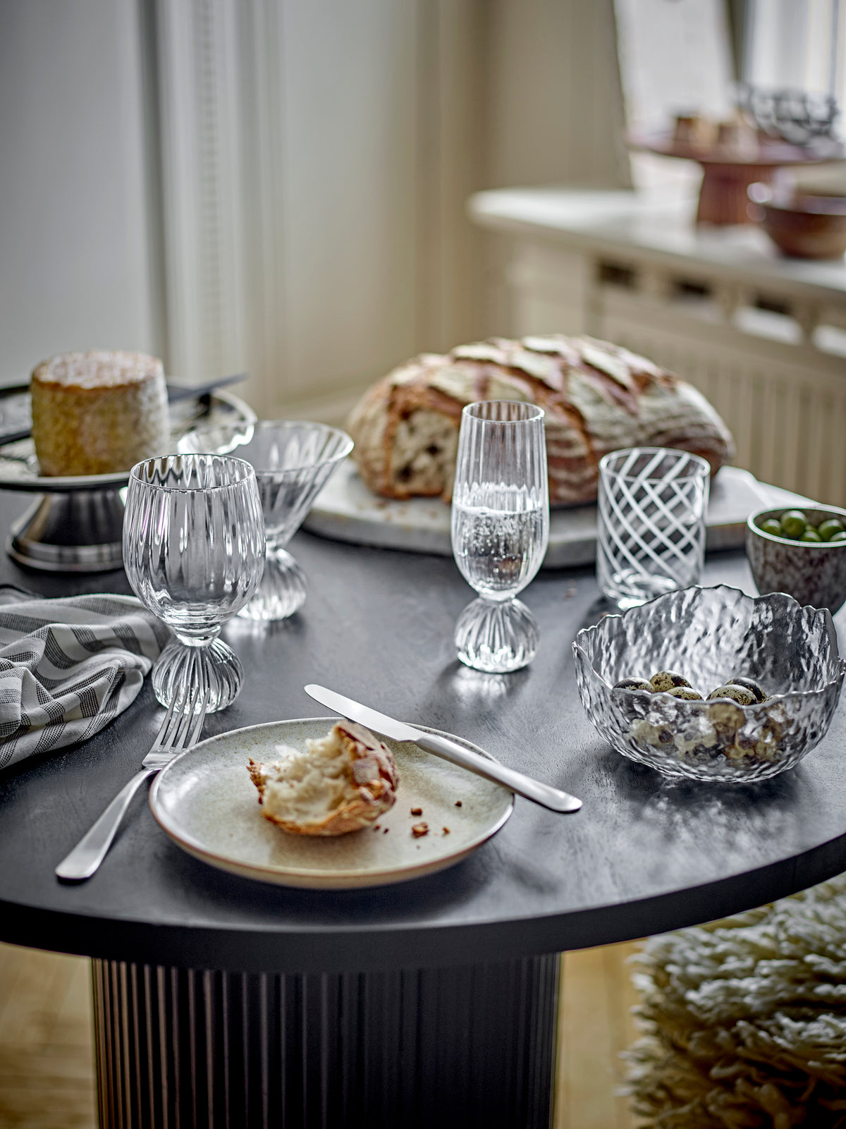 Taurin glasses on a round dark table with sourdough bread, a plate and a glass bowl