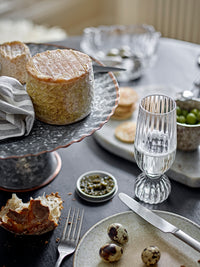 Taurin champagne glass styled on a dining table with cheese, olives, and matching glassware
