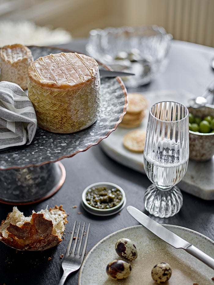 Taurin champagne glass styled on a dining table with cheese, olives, and matching glassware
