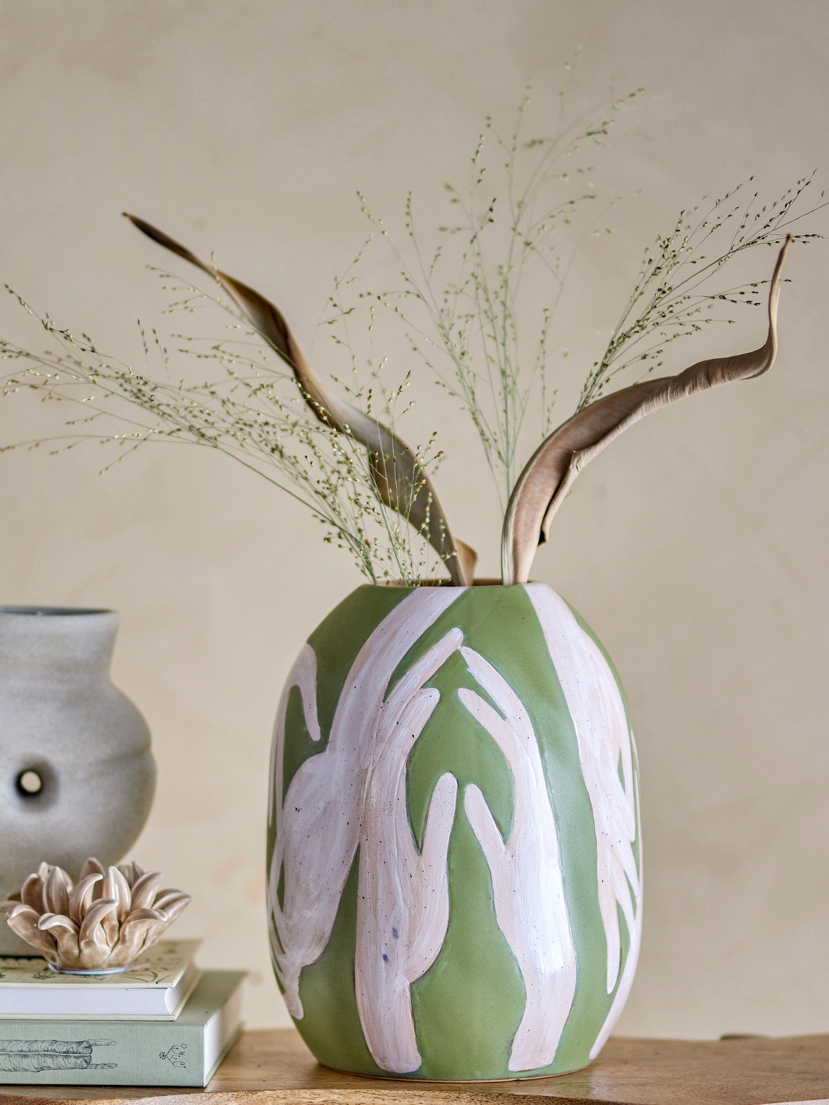 Adalena green vase styled on a wooden side table with foliage