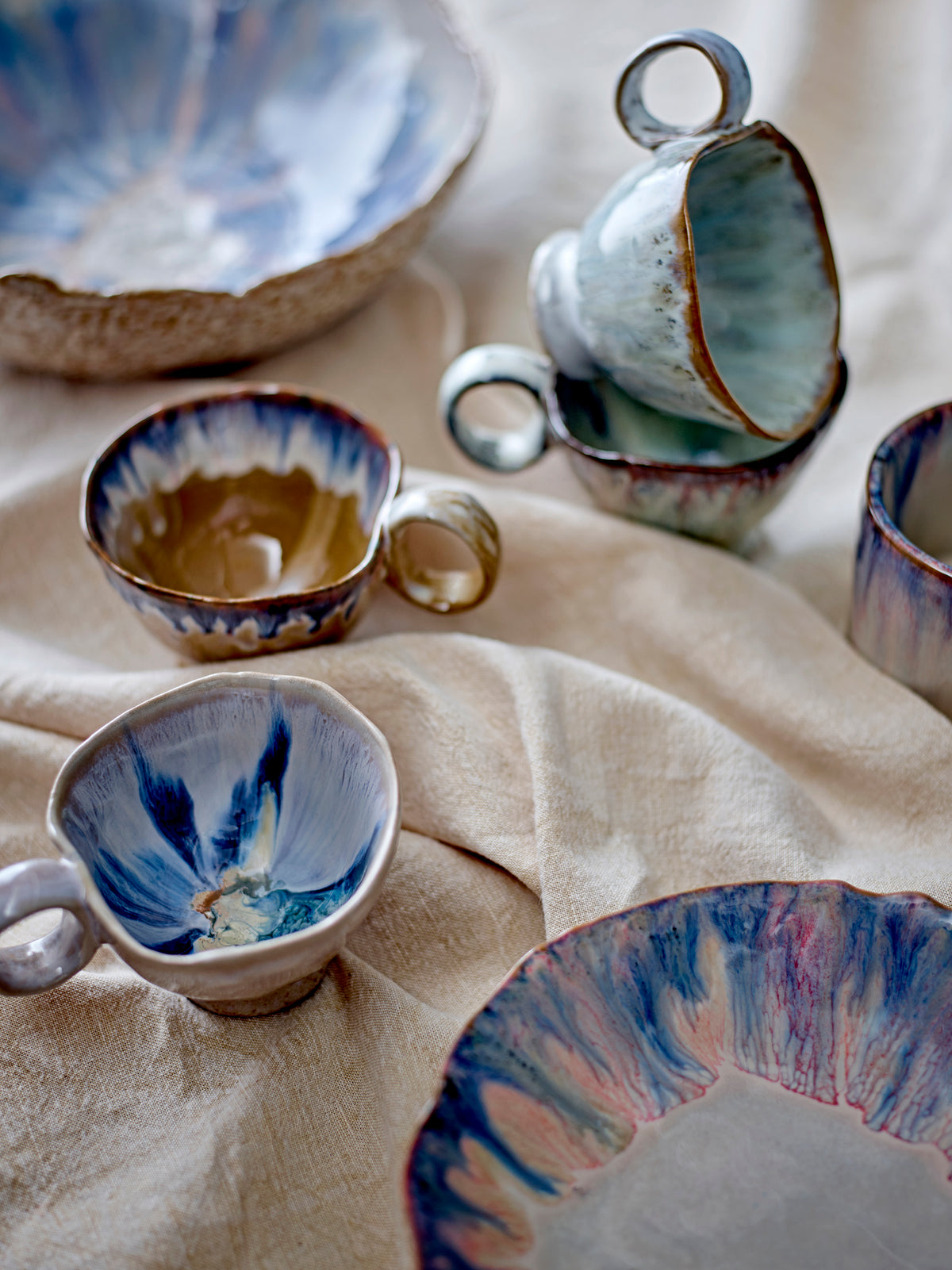 Imogen cups in blue and brown displayed with matching plates and mugs
