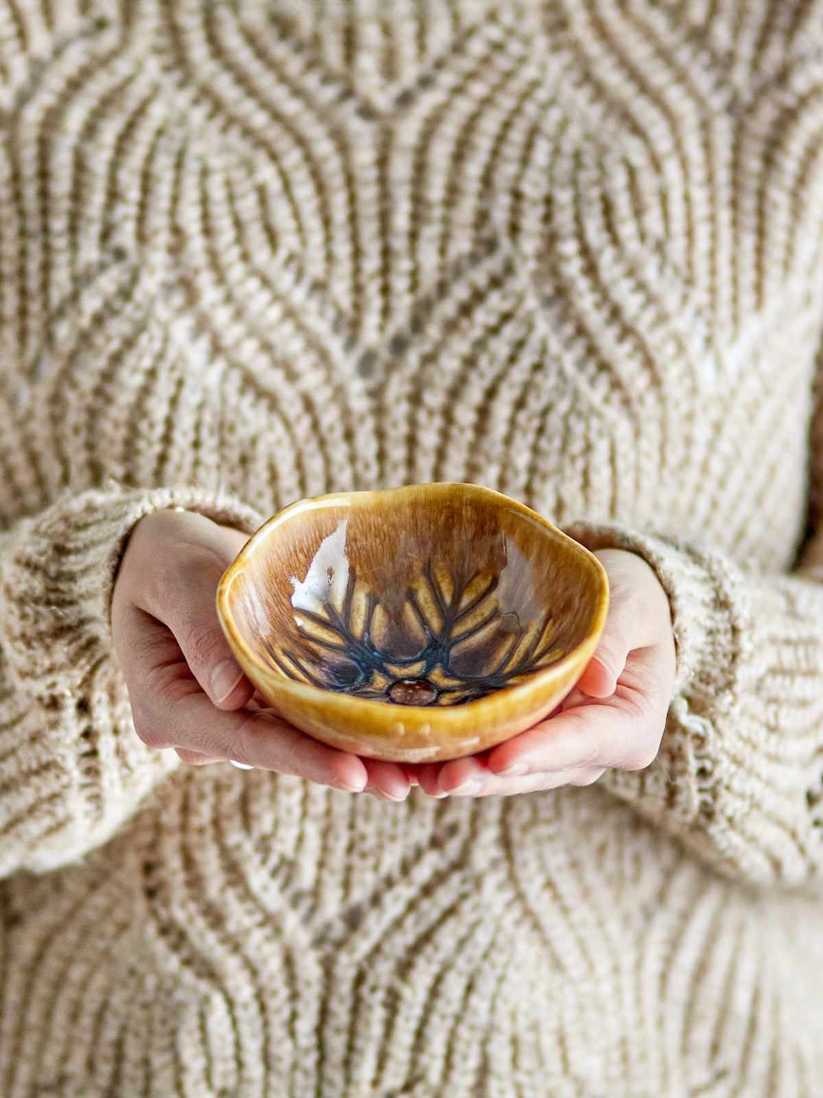 Acco bowl brown stoneware with snowflake motif, held in hand
