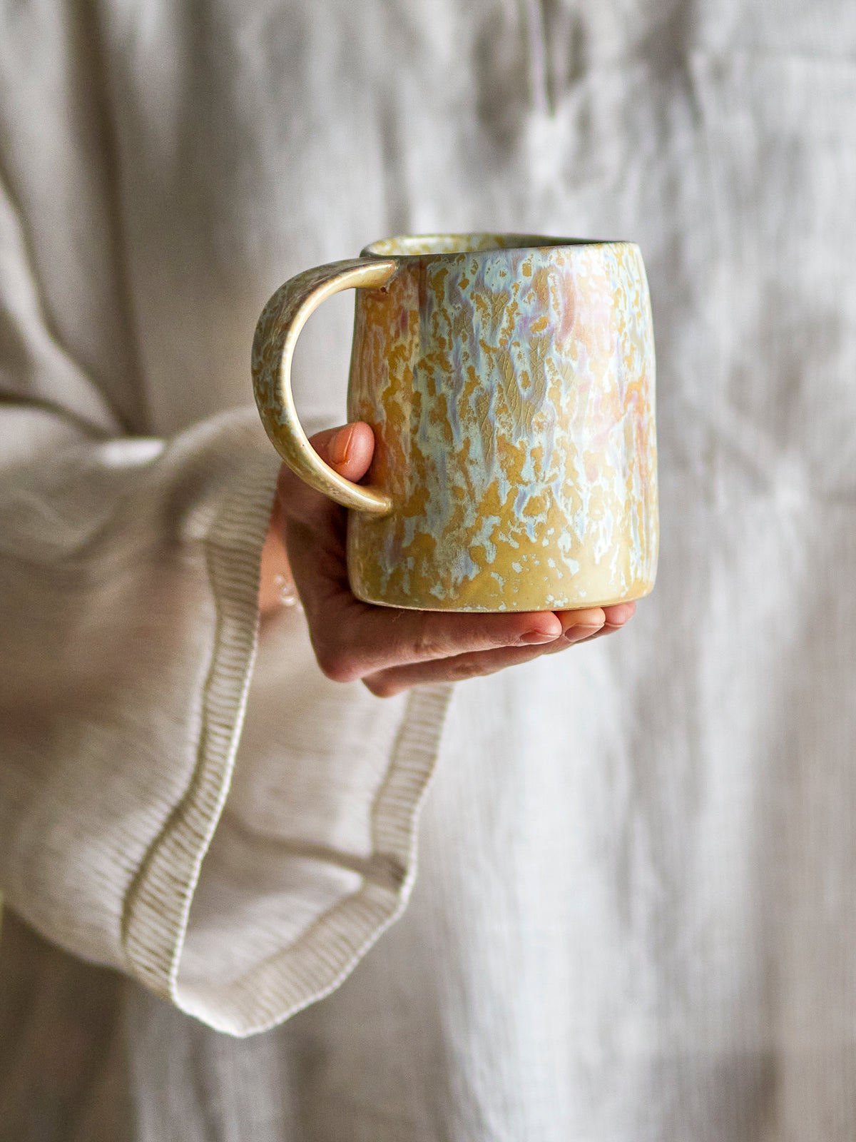 Yori mug by Bloomingville held in hand, showing colourful reactive glaze
