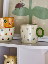 Dorthea cup with nature colour and floral pattern displayed on a kids’ shelf
