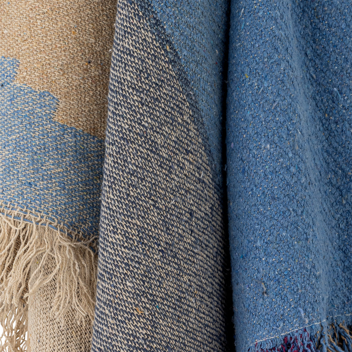 Close-up of textured fabric with fringes in blue and beige tones.