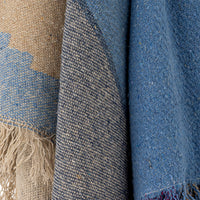 Close-up of textured fabric with fringes in blue and beige tones.