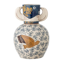Hezha navy blue stoneware vase styled in a living room beside a rattan chair and white display cabinet