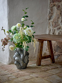 Vuelle grey vase with white floral arrangement beside a wooden bench