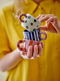 person stacking colourful bloomingville mini cups including the nature nini cup
