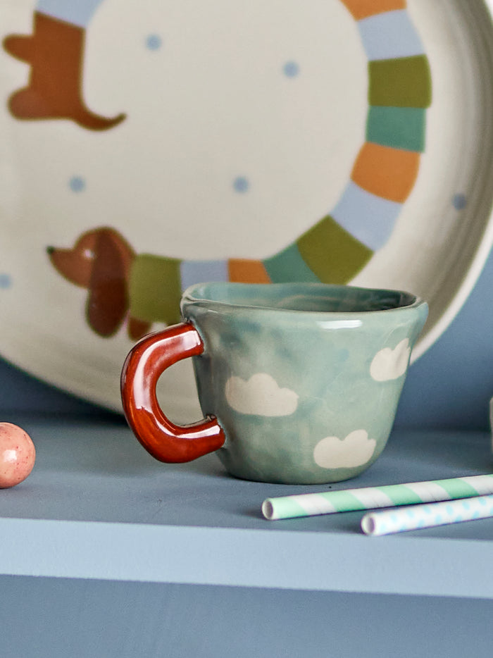 blue cloud-pattern nini cup styled on children’s shelf with striped plate
