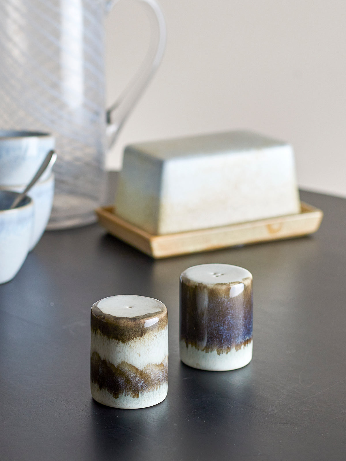 close-up of grey reactive-glaze Paula salt and pepper shakers on a dark tabletop