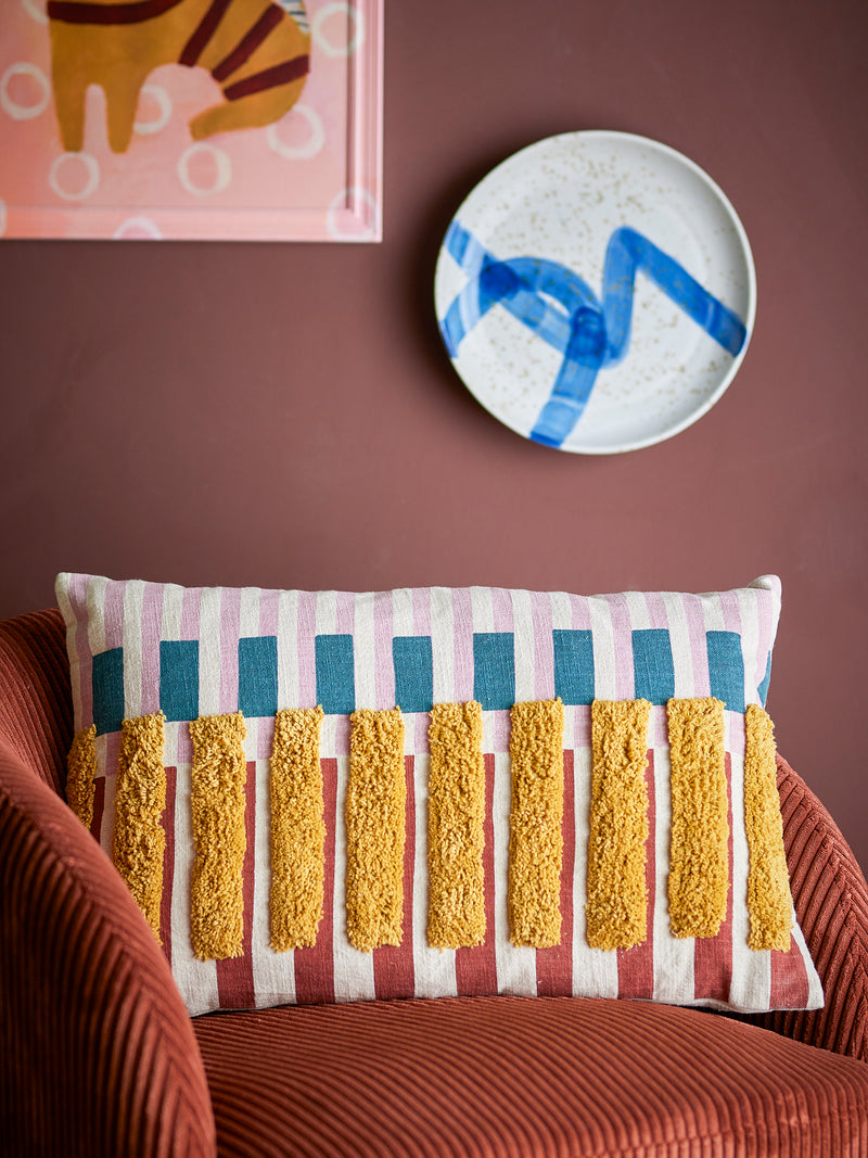 Lane Cushion with piano key like style placed on a rust-coloured armchair against a warm-toned wall