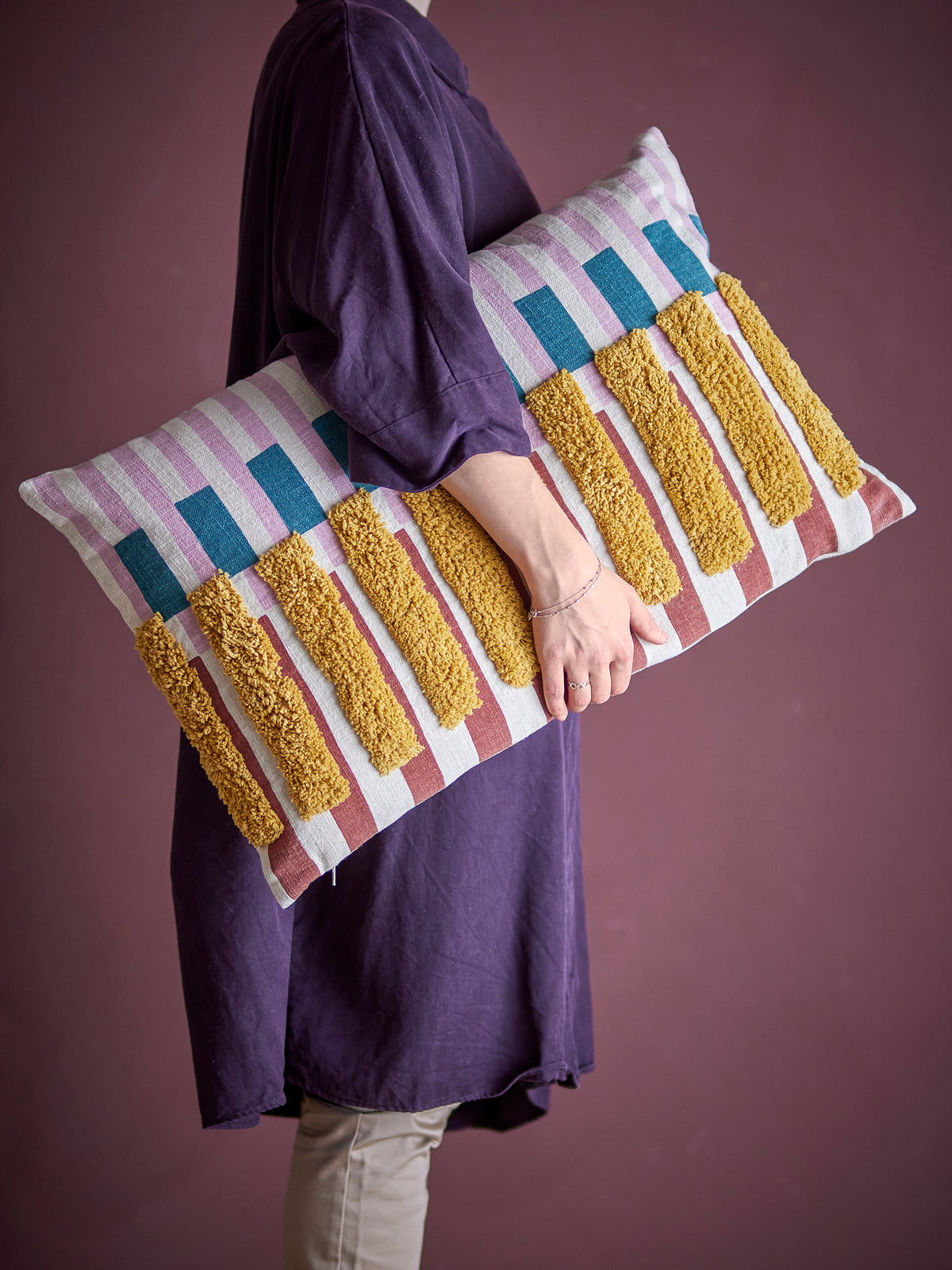 Person holding the Lane Cushion to show size and textured tufted stripes

