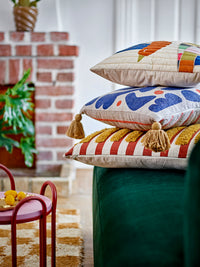 Stack of patterned cushions including the Lane Cushion with yellow tufted stripes
