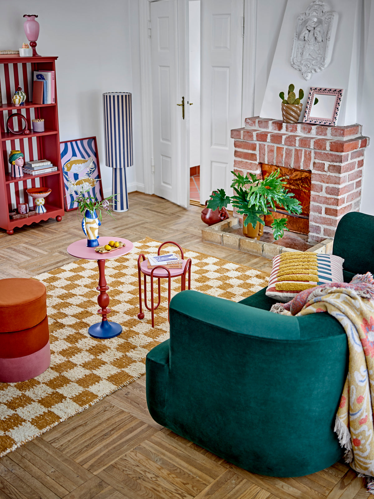 Living room scene with colourful décor featuring the Lane Cushion on a green sofa
