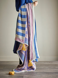 Arlie blue throw draped over the arm of a model showing swirl pattern and tassels