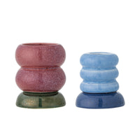 Two stacked Tana candle holders, dusty pink on dark green and light blue on navy, on a white background